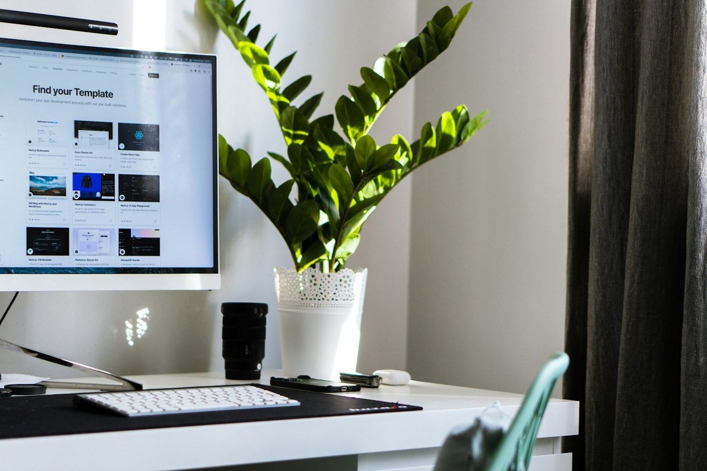 Computer monitor displaying website templates next to a potted plant.